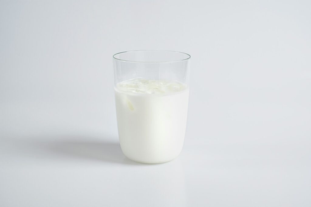 Glas melk met ijsblokjes als symbool voor allergieën en hormonen bij koemelkallergie.