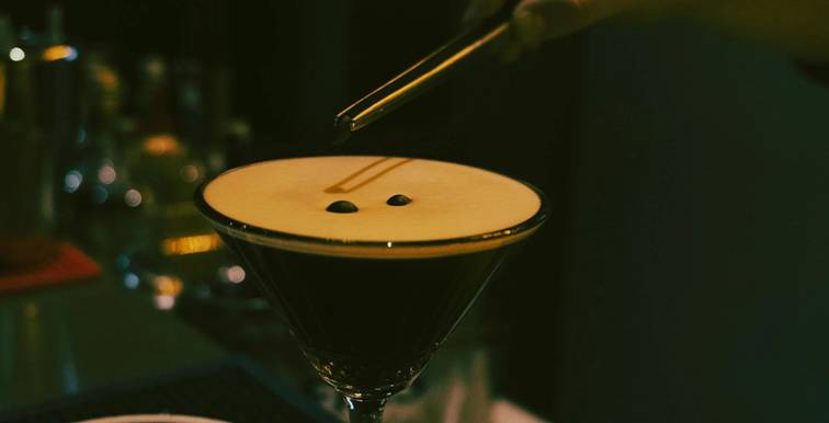 Close-up van een Espresso Martini met schuimlaag en drie koffiebonen, geserveerd in een martiniglas